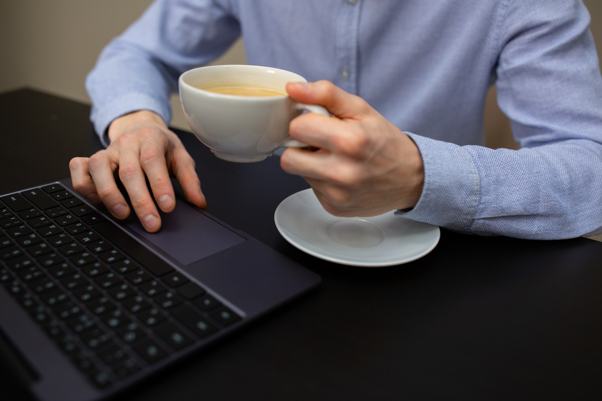 Man achter zijn laptop met remote monitoring en management software en een kop koffie